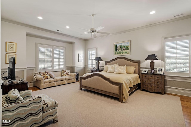 bedroom with crown molding, ceiling fan, hardwood / wood-style floors, and multiple windows