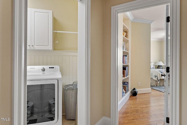 washroom with washer / clothes dryer, ornamental molding, light hardwood / wood-style floors, and cabinets