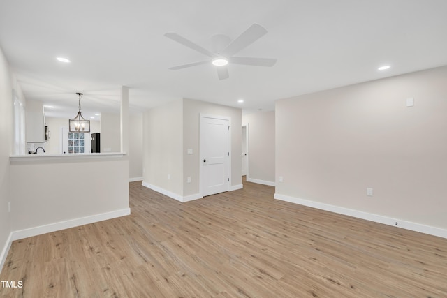 spare room featuring ceiling fan with notable chandelier and light hardwood / wood-style flooring