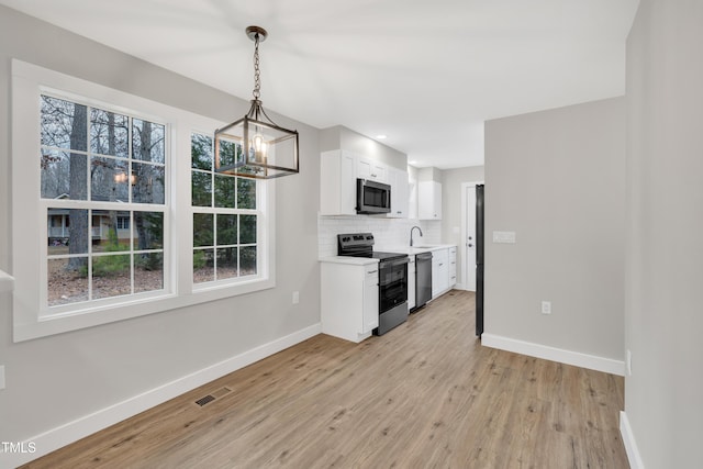 kitchen with white cabinetry, hanging light fixtures, tasteful backsplash, and stainless steel appliances