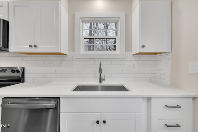 kitchen featuring tasteful backsplash, white cabinetry, appliances with stainless steel finishes, and sink