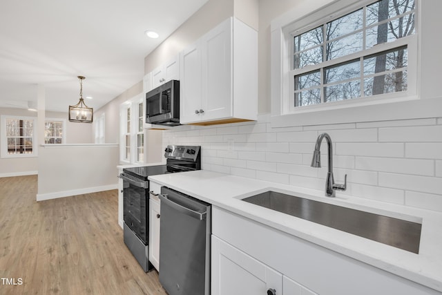 kitchen with sink, white cabinets, decorative backsplash, hanging light fixtures, and stainless steel appliances