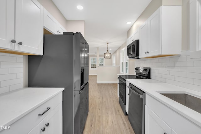 kitchen featuring stainless steel appliances, decorative light fixtures, light wood-type flooring, and white cabinets