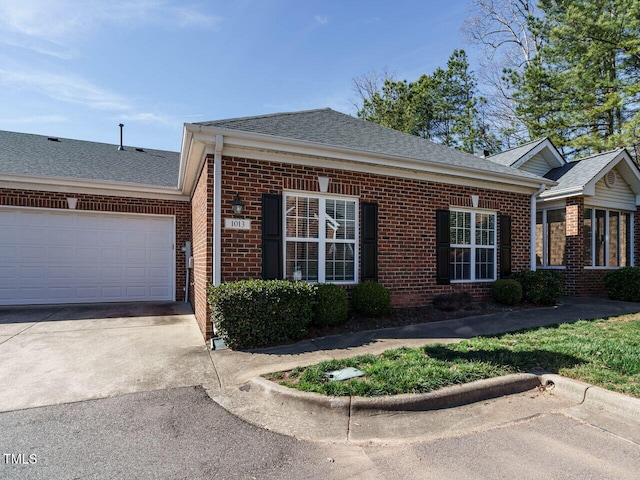 view of front of home featuring a garage, driveway, brick siding, and roof with shingles