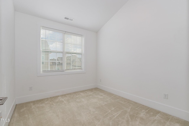 carpeted empty room featuring lofted ceiling