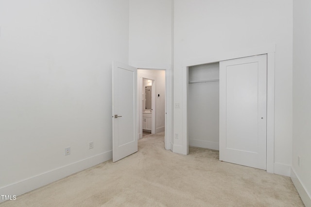 unfurnished bedroom with light colored carpet, a closet, and a high ceiling