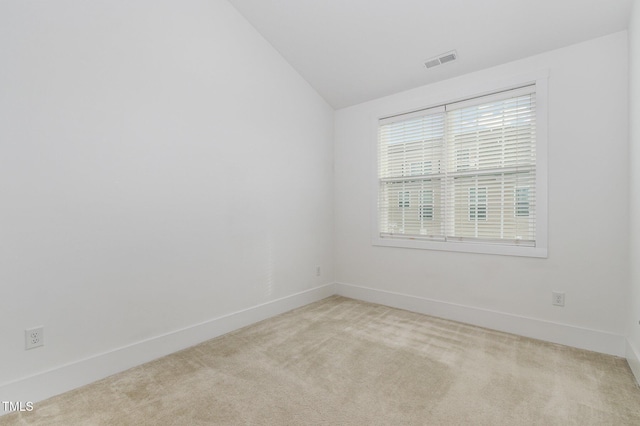 unfurnished room featuring vaulted ceiling and light colored carpet