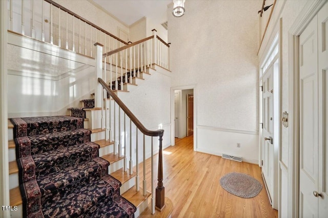 stairs with hardwood / wood-style floors and a towering ceiling