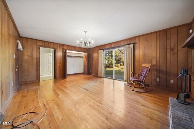 interior space with a notable chandelier, crown molding, wooden walls, and light hardwood / wood-style floors