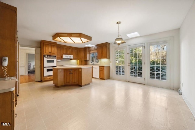 kitchen with a kitchen island, white appliances, and decorative light fixtures