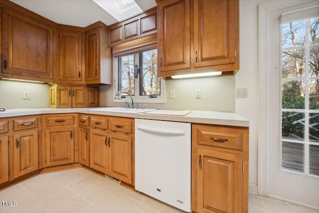 kitchen with white dishwasher, a skylight, and sink