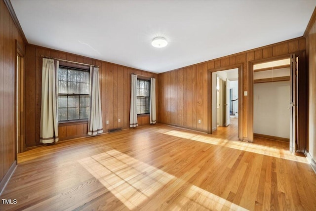 unfurnished room featuring light hardwood / wood-style flooring and wood walls