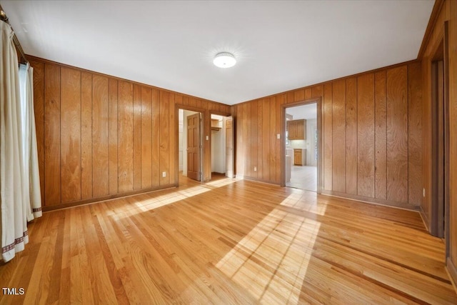 unfurnished room featuring light hardwood / wood-style floors and wood walls