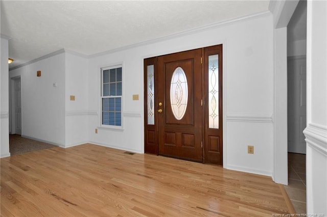 foyer with ornamental molding and light wood-type flooring