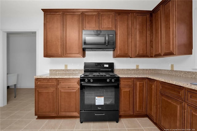 kitchen with light stone counters, light tile patterned floors, and black appliances