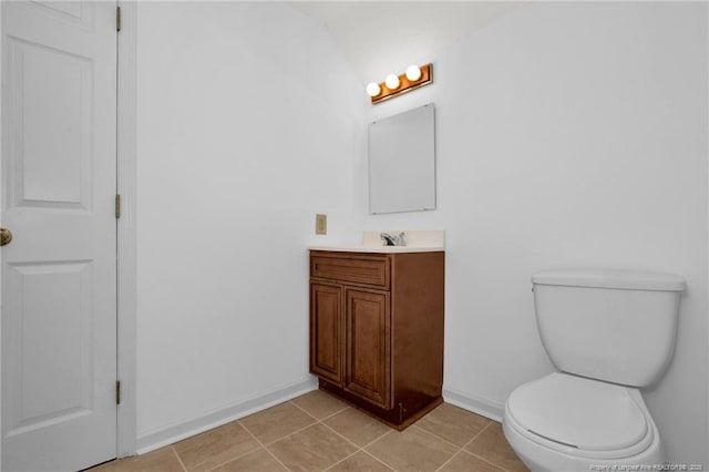 bathroom with vanity, tile patterned flooring, lofted ceiling, and toilet