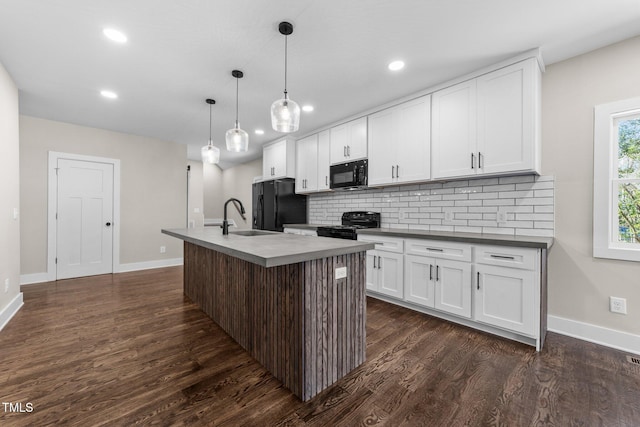 kitchen with hanging light fixtures, black appliances, an island with sink, and white cabinets