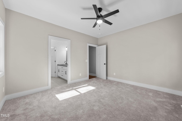 unfurnished bedroom featuring ceiling fan, connected bathroom, sink, and light carpet