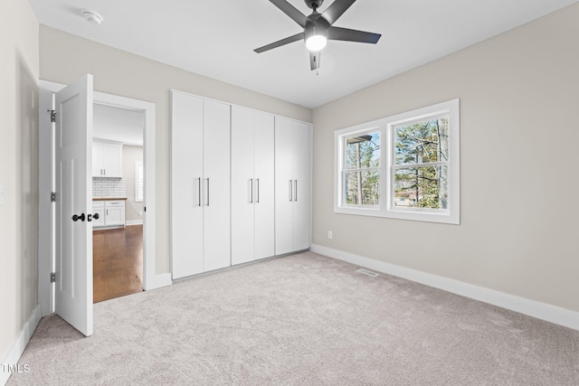 unfurnished bedroom featuring light carpet, a closet, and ceiling fan