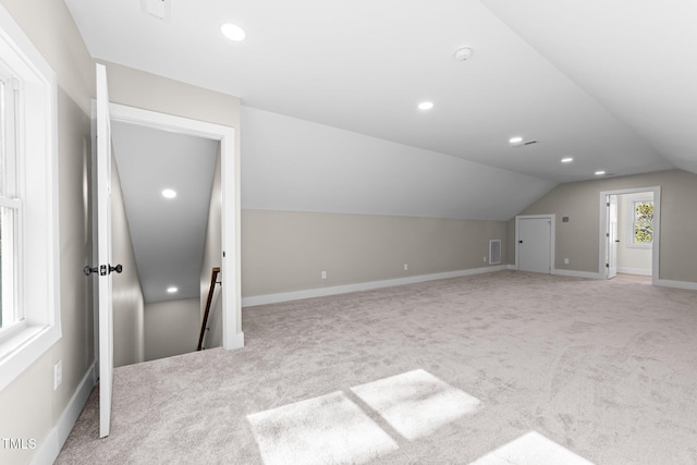 bonus room with lofted ceiling and light carpet