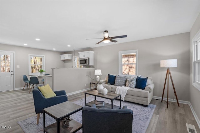 living room featuring light wood finished floors, baseboards, visible vents, and recessed lighting