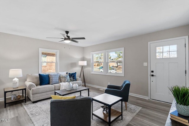 living area with ceiling fan, light wood-type flooring, and baseboards