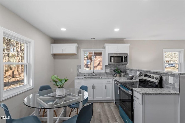 kitchen featuring white cabinets, a wealth of natural light, stainless steel appliances, and a sink