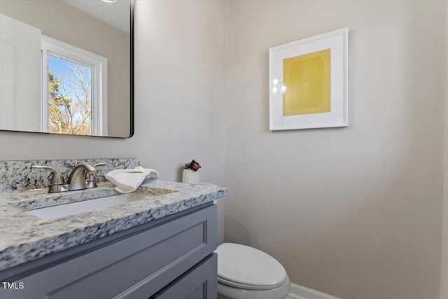 bathroom with vanity, toilet, and baseboards