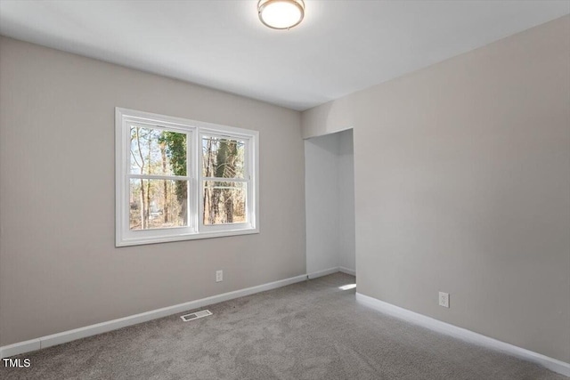 empty room featuring carpet, visible vents, and baseboards