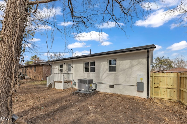 rear view of house with crawl space, fence, central AC unit, and brick siding