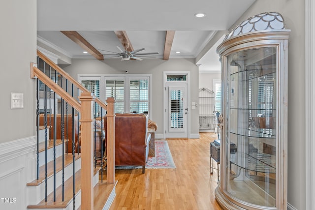 interior space with ceiling fan, crown molding, beam ceiling, and light hardwood / wood-style floors