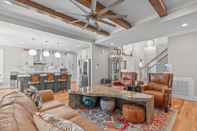 living room featuring ceiling fan with notable chandelier, beamed ceiling, sink, light hardwood / wood-style floors, and crown molding