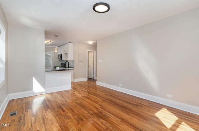 unfurnished living room featuring sink and light hardwood / wood-style floors