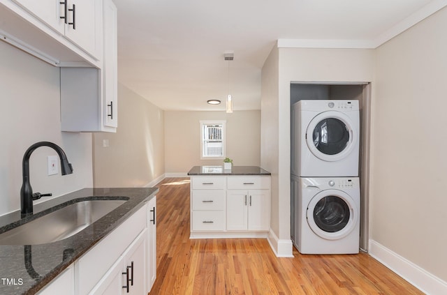 washroom with sink, stacked washer / drying machine, and light wood-type flooring