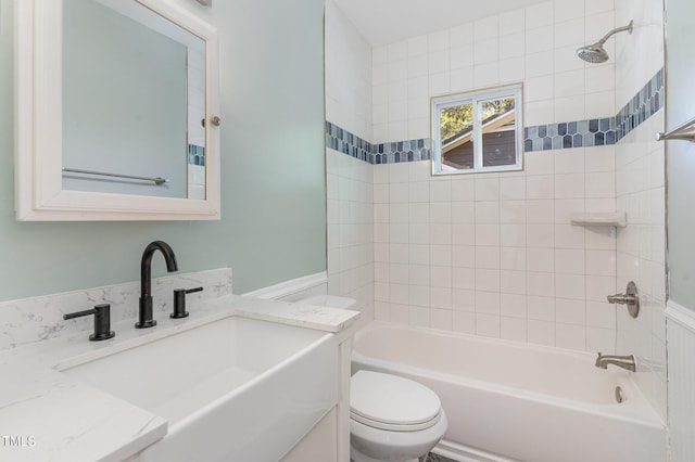 full bathroom featuring vanity, tiled shower / bath combo, and toilet