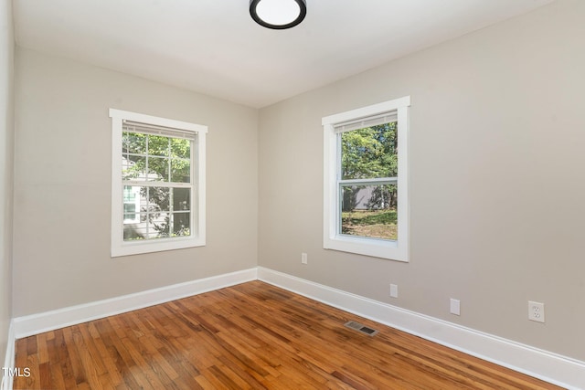 empty room featuring a healthy amount of sunlight and hardwood / wood-style floors