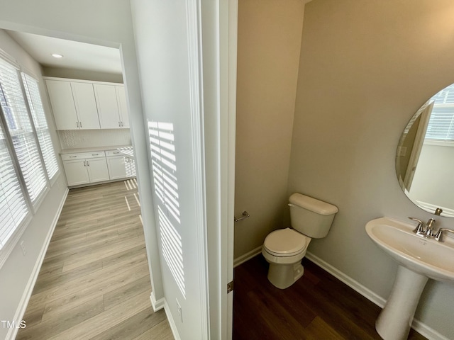 bathroom featuring tasteful backsplash, wood-type flooring, toilet, and sink