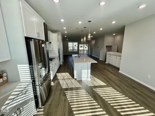 kitchen with white cabinetry, decorative light fixtures, stainless steel fridge with ice dispenser, a center island with sink, and dark hardwood / wood-style flooring