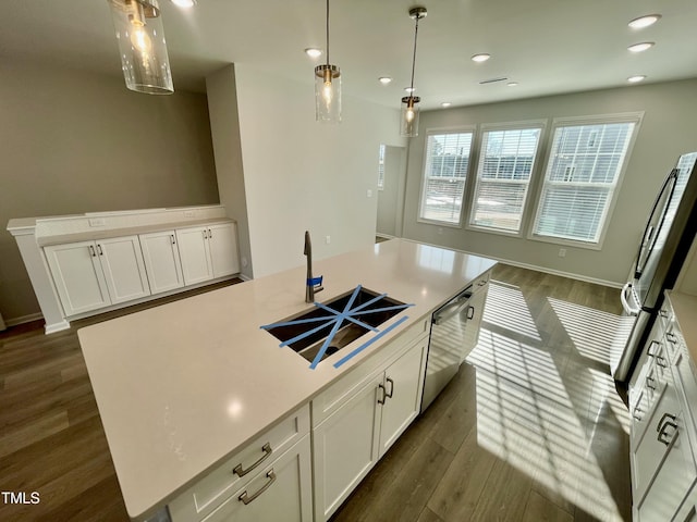 kitchen with stainless steel appliances, a kitchen island with sink, white cabinets, and decorative light fixtures