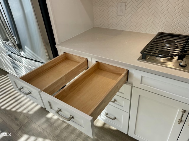 interior space featuring white cabinets, stainless steel gas cooktop, and backsplash