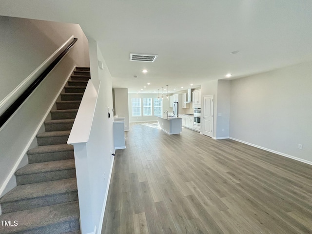 staircase featuring hardwood / wood-style floors and sink