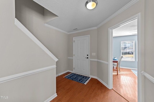 foyer entrance with wood-type flooring, crown molding, and a textured ceiling