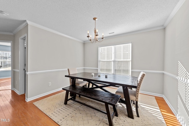 dining space featuring crown molding, a notable chandelier, and light hardwood / wood-style floors