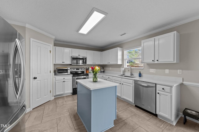 kitchen with sink, appliances with stainless steel finishes, white cabinetry, ornamental molding, and a kitchen island