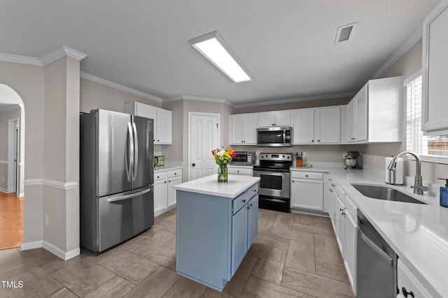 kitchen featuring a kitchen island, appliances with stainless steel finishes, white cabinetry, sink, and crown molding