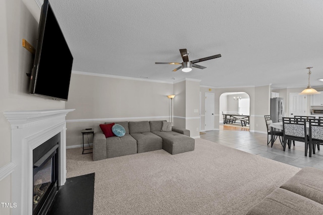 living room featuring light tile patterned floors, crown molding, a textured ceiling, and ceiling fan