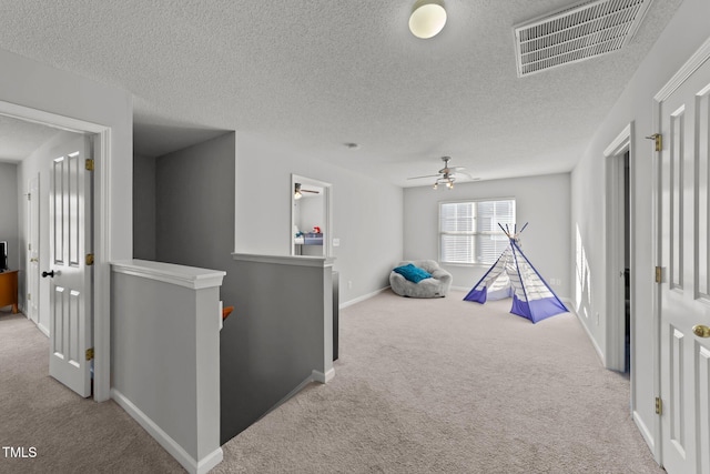 game room with ceiling fan, light carpet, and a textured ceiling