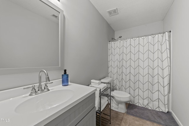 bathroom with tile patterned flooring, vanity, a textured ceiling, and toilet