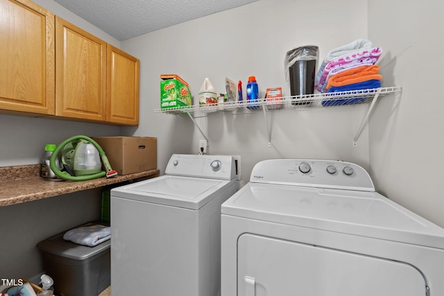 laundry room featuring cabinets, washer and dryer, and a textured ceiling