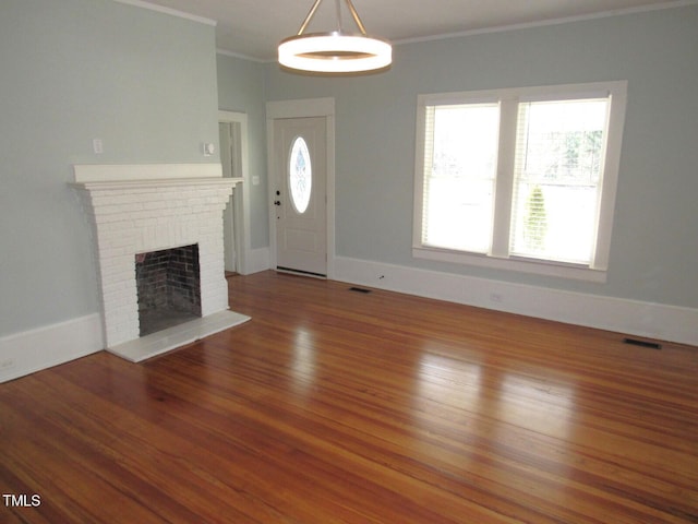 unfurnished living room featuring crown molding, hardwood / wood-style floors, and a brick fireplace